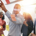 Businesspeople brainstorming together with sticky notes in an office How To Build A High Performance Team in the Workplace concept